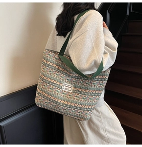 Detailed side view of ethnic pattern tote bag with green strap worn by model