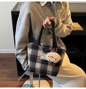 Detail of checkered tote bag fabric texture with a plush bear keychain accessory