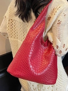 Red woven leather large hobo tote bag for women worn over shoulder with beige knitwear