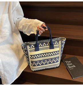 Close-up of blue and white geometric canvas tote bag with woven straps on a wooden step