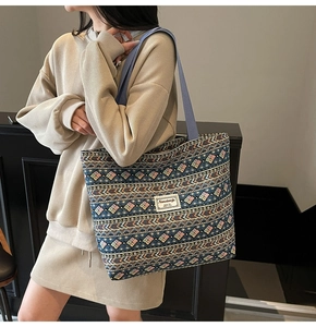 Detail of ethnic geometric patterned tote bag with blue fabric shoulder strap on model