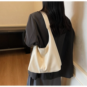 Detail of creamy white tote bag featuring soft pleated faux leather texture on shoulder