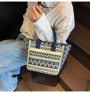 Close-up of durable canvas tote bag featuring navy blue geometric patterns and sturdy handles