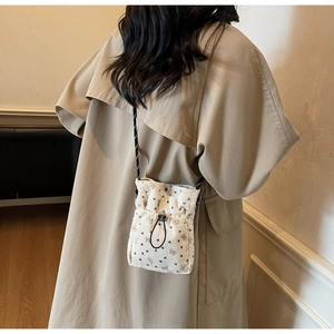 Detail of cream corduroy crossbody bag with butterfly prints and adjustable drawstring