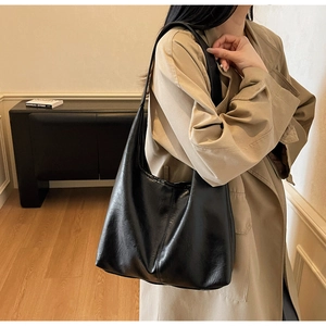 Close-up of black leather texture tote bag styled with a minimalist beige trench coat