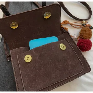 Dettaglio borsa a tracolla marrone vintage con fibbia dorata e ciondolo nappa