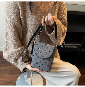 Detail showing grey tweed fabric with black dots and silver metal bow on a mini bag
