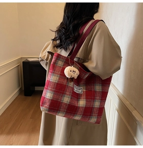 Detail of red checkered canvas tote bag with shoulder strap and plush bear charm