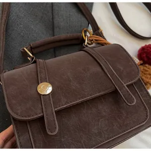 Dettaglio ravvicinato della borsa vintage marrone scuro con fibbie dorate e texture