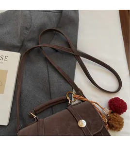 Dettaglio borsa vintage marrone con tracolla lunga liscia e fibbia in metallo rotonda