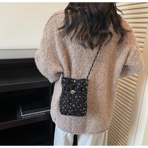 Detail of a black corduroy mini crossbody bag featuring white floral butterfly patterns