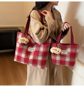 Detail of red plaid tote bag with luxury texture and cute plush sheep charm