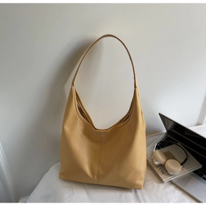 Detail of a large yellow faux leather tote bag in a minimalist office setting
