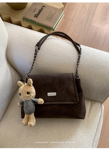 Détail du sac à bandoulière en daim marron foncé avec chaîne et breloque lapin mignon
