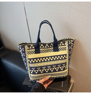 Detail of canvas tote bag with geometric woven patterns and blue webbing handles