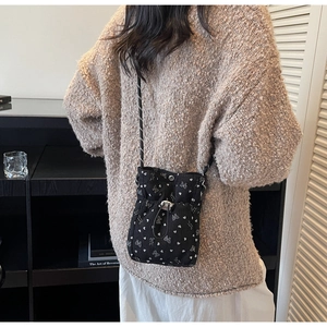 Detail of black corduroy drawstring phone bag with white bow and heart prints