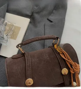 Dettaglio della borsa in pelle marrone vintage con fibbia dorata e ciondolo intrecciato