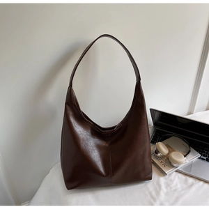 Detail of dark brown faux leather tote with waxy texture for office commuting