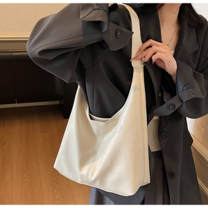 Detail of minimalist beige oversized tote bag featuring a wide shoulder strap and soft PU leather