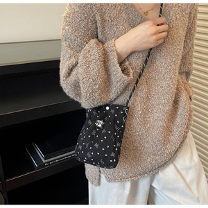 Detail of black crossbody bag with white heart patterns and a woven drawstring pocket