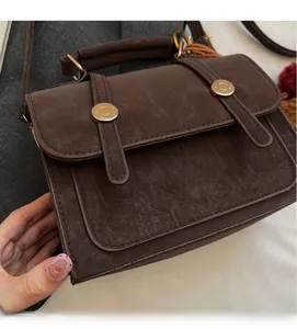 Dettaglio borsa a tracolla vintage marrone scuro con fibbie in metallo e manico