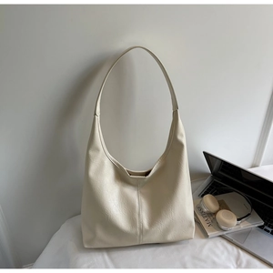 Close-up of minimalist cream tote bag showing vertical stitching and lychee leather texture