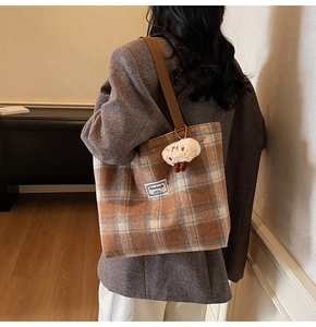 Detailed close-up of brown plaid wool tote bag featuring a cute mushroom plush charm
