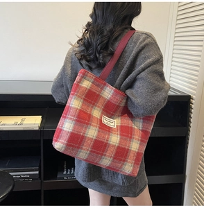 Detail of red and beige checkered tote bag with woven shoulder strap and wool texture