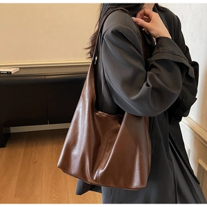 Detail view of large brown faux leather tote bag showing soft texture and glossy finish