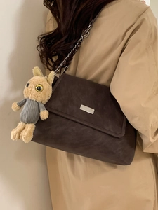 Sac bandoulière en daim marron foncé avec chaîne et breloque lapin sur le mannequin