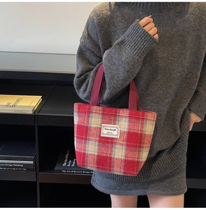 Detail view of red plaid tweed tote bag with woven texture and premium fabric handles