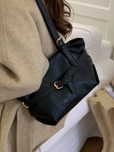 Classic black leather underarm shoulder bag with gold buckle on a stylish model