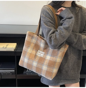 Close-up of brown plaid tote bag texture with white woven label on autumn sweater