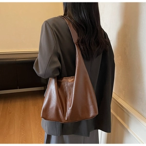 Detail view of large dark brown tote bag showing supple leather texture and fit on shoulder
