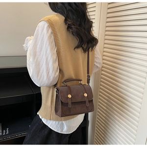 Dettaglio della borsa a tracolla vintage marrone con fibbia metallica e pelle PU testurizzata