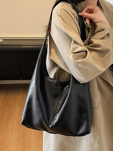 Minimalist large capacity black leather tote bag shown on model in warm indoor setting