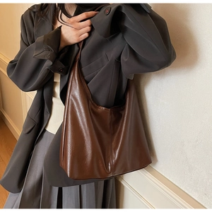 Detail of a large dark brown faux leather tote bag showing smooth texture and slouchy shape