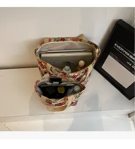 Détail de grands sacs cabas en toile à fleurs montrant l'espace pour ordinateur et livres
