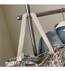 Detail of floral canvas tote bag showing wide woven handles and vintage butterfly print