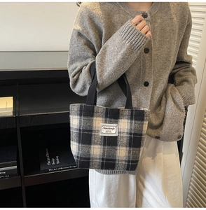 Detail shot of a black and white plaid tote bag with sturdy black handles and cloth label