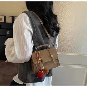 Dettaglio borsa a tracolla stile inglese con trama in pelle vintage e ciondolo a pompon