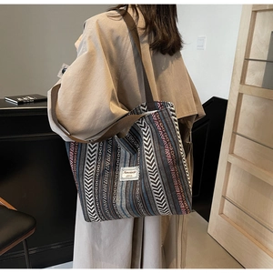 Detailed texture of ethnic striped woven tote bag featuring canvas shoulder straps