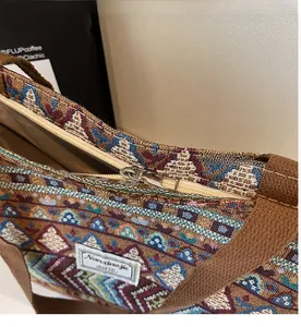 Close-up of smooth silver metal zipper and bohemian jacquard fabric on tote bag