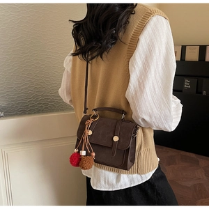 Dettaglio della borsa a tracolla vintage marrone scuro con cinghie e ciondolo a pompon