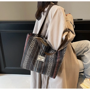 Detail of large woven tote bag with geometric arrow patterns and brown strap