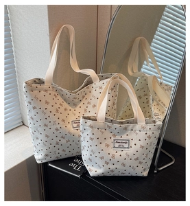 Detailed view of corduroy tote bag set with heart and bow prints on wooden table