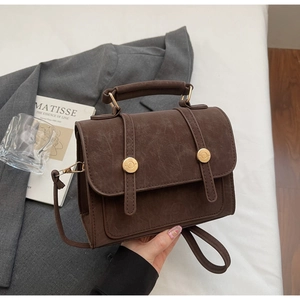 Dettaglio ravvicinato della trama in finta pelle vintage di questa borsa marrone a mano
