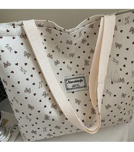 Detailed texture of corduroy tote bag featuring brown bow and heart patterns