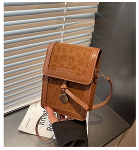 Detail of vintage leopard print crossbody phone bag with embossed logo and metal tag