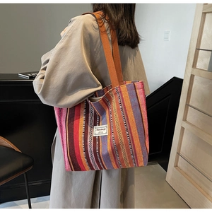 Detail of colorful striped woven canvas tote bag with wide shoulder straps and label